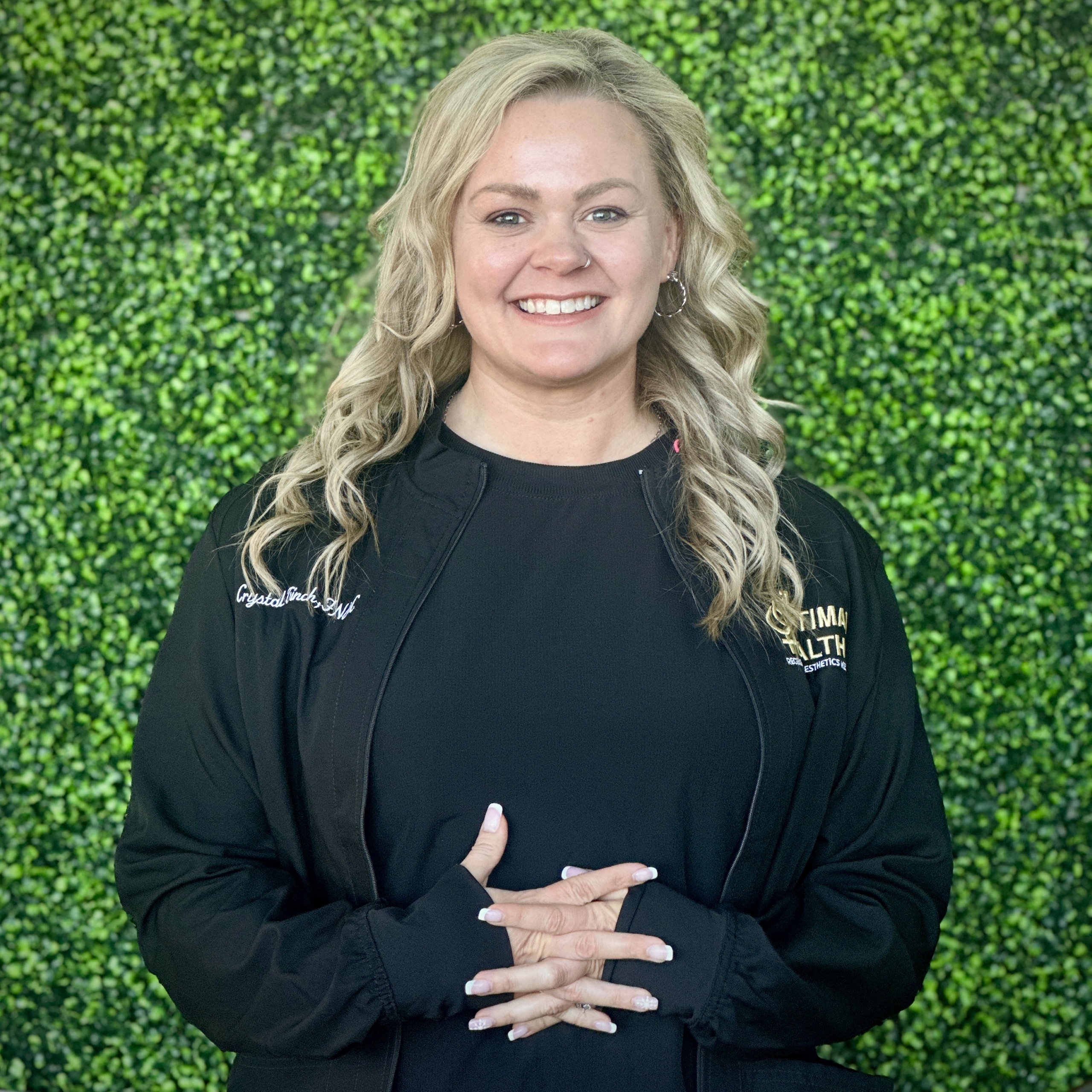 Headshot of nurse standing in front of wall covered in vines